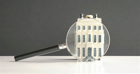 Magnify glass over a house figurine