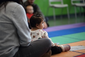 a baby sits on her mom's lap and listens to a story