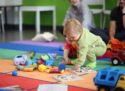 a baby stoops to pick up a toy at the end of baby story time