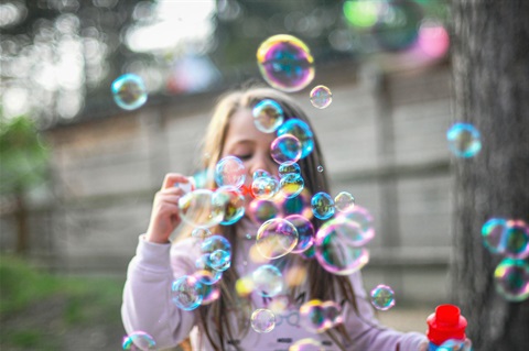 Little girl blowing a lot of bubbles outside