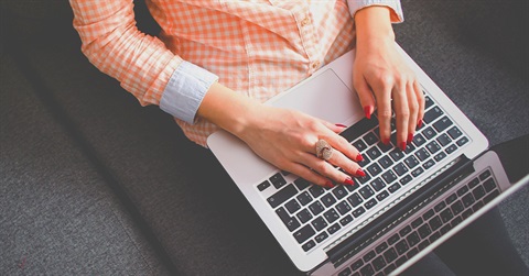 adult writing on computer