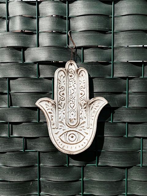 A Hamsa ornament hanging from a weaved texture