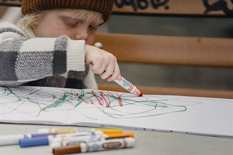 child scribbling on white paper