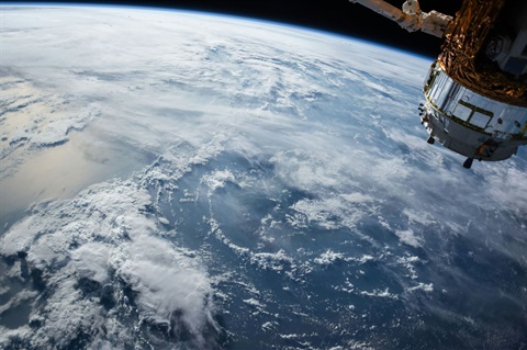 Earth viewed from space with the space station visible coming in from the right side. 