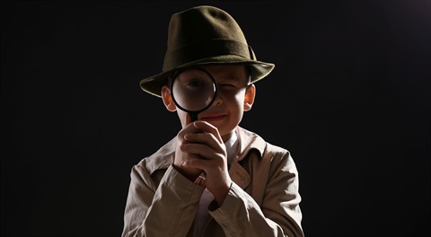 Child in spy detective attire with magnify glass