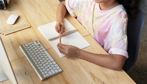 Teen using computer with notepad