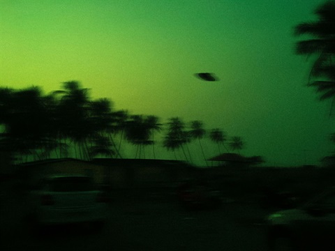 Picture with mysterious, green hue and a UFO in the sky